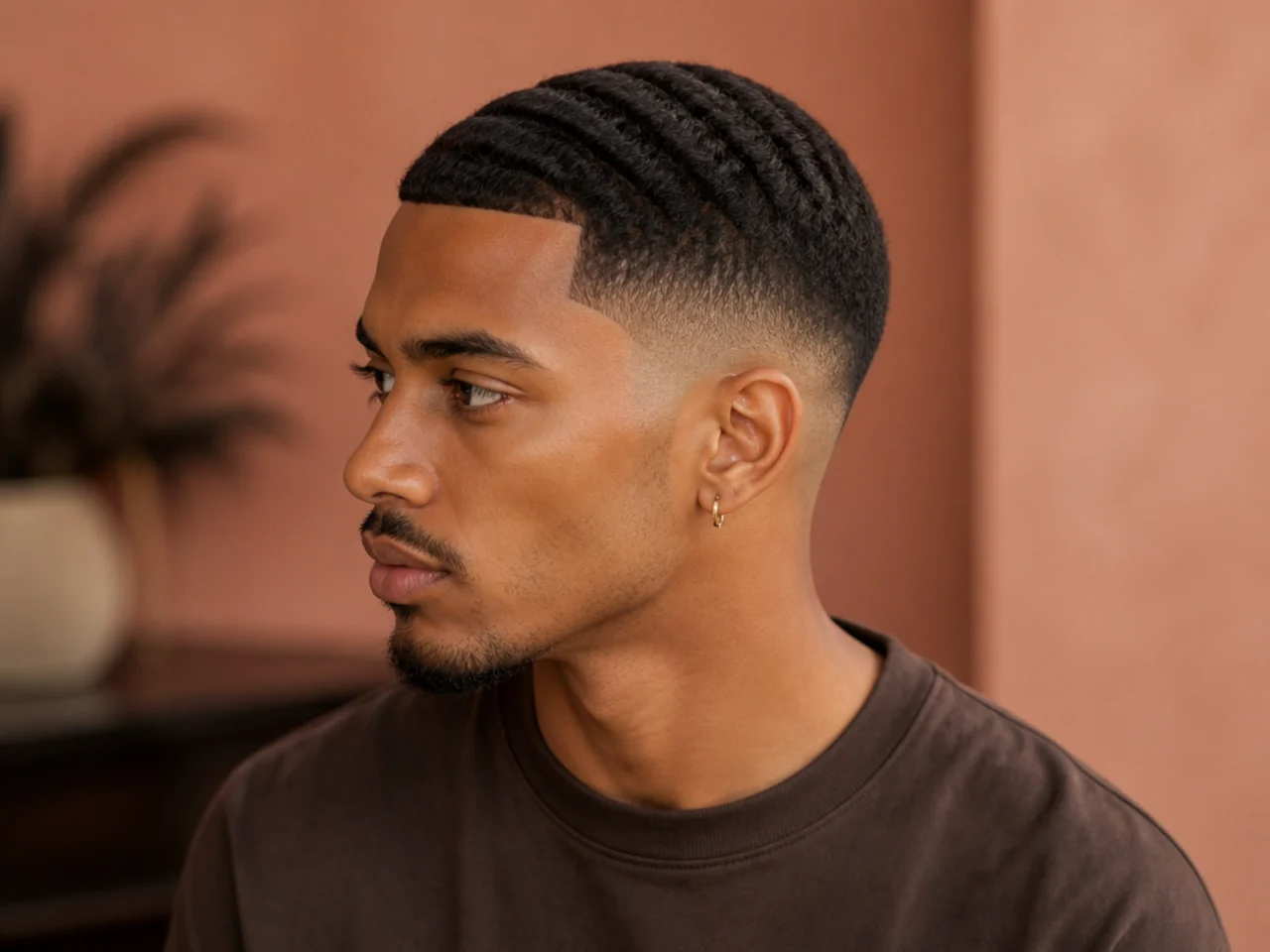 Three parallel wave lines shaved through a low burst fade on a man with medium wavy hair