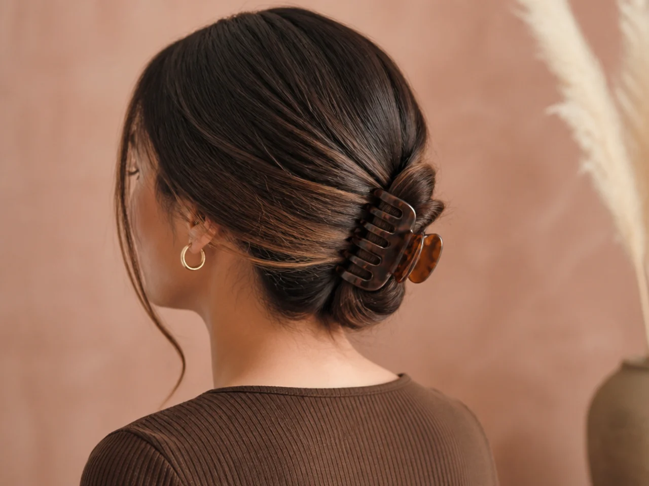 A claw clip fastened low at the nape