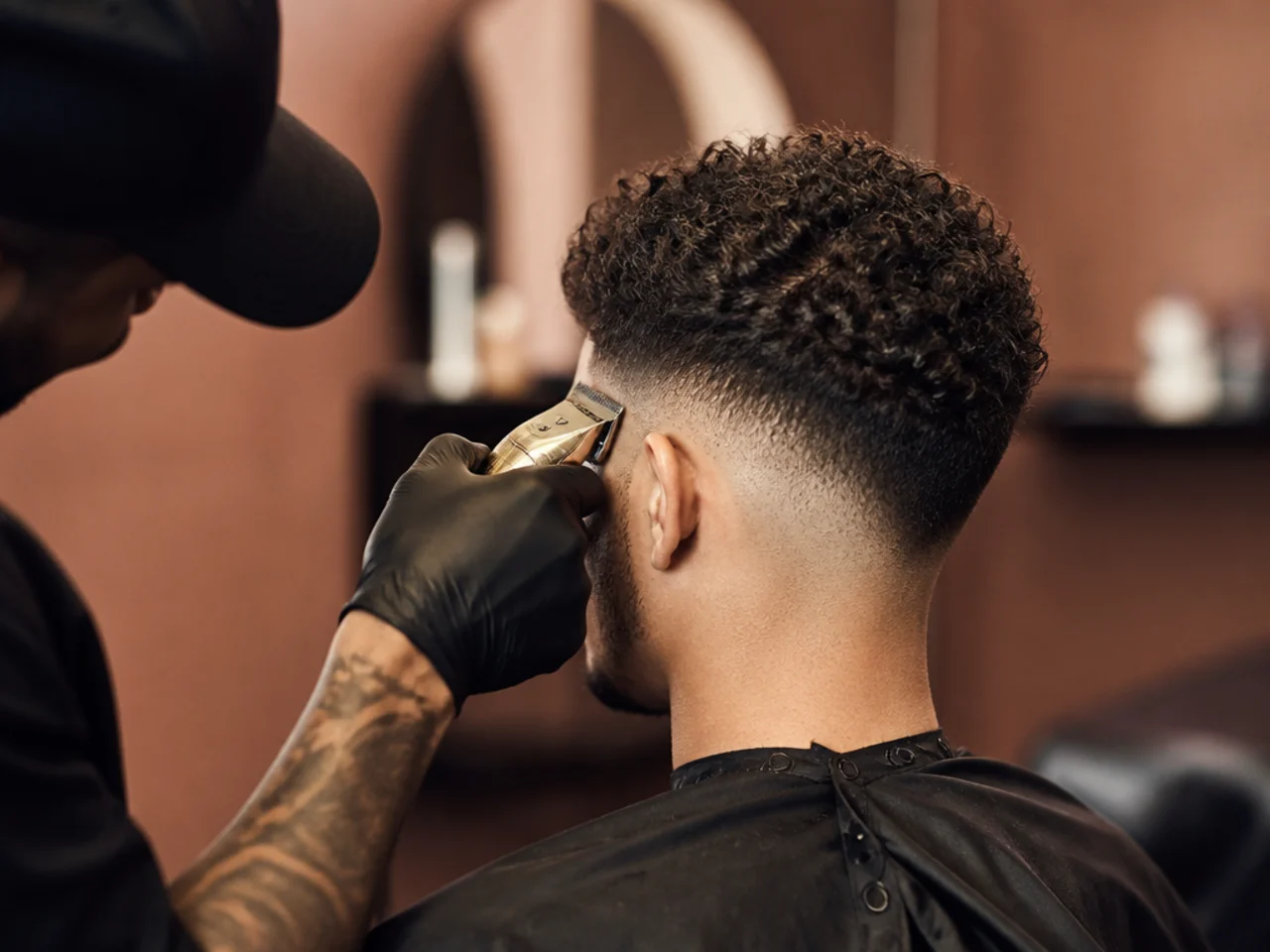 A barber blending the top edge of a fade into curls