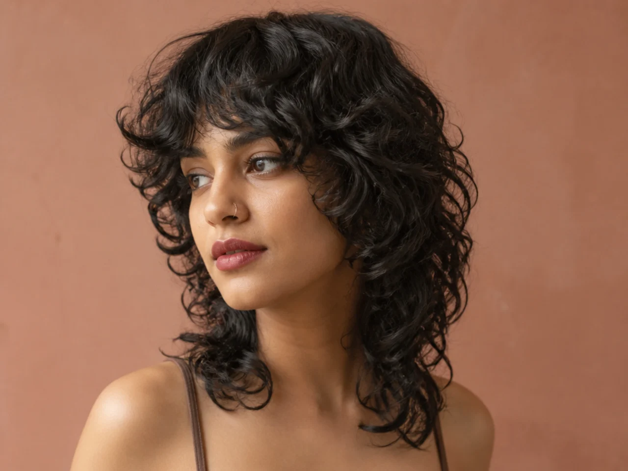 A curly mullet with curtain bangs framing the face