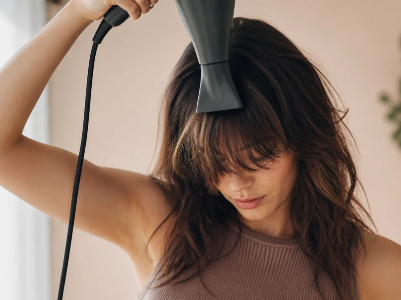 A fringe being dried forward over the face with a nozzle pointed downward