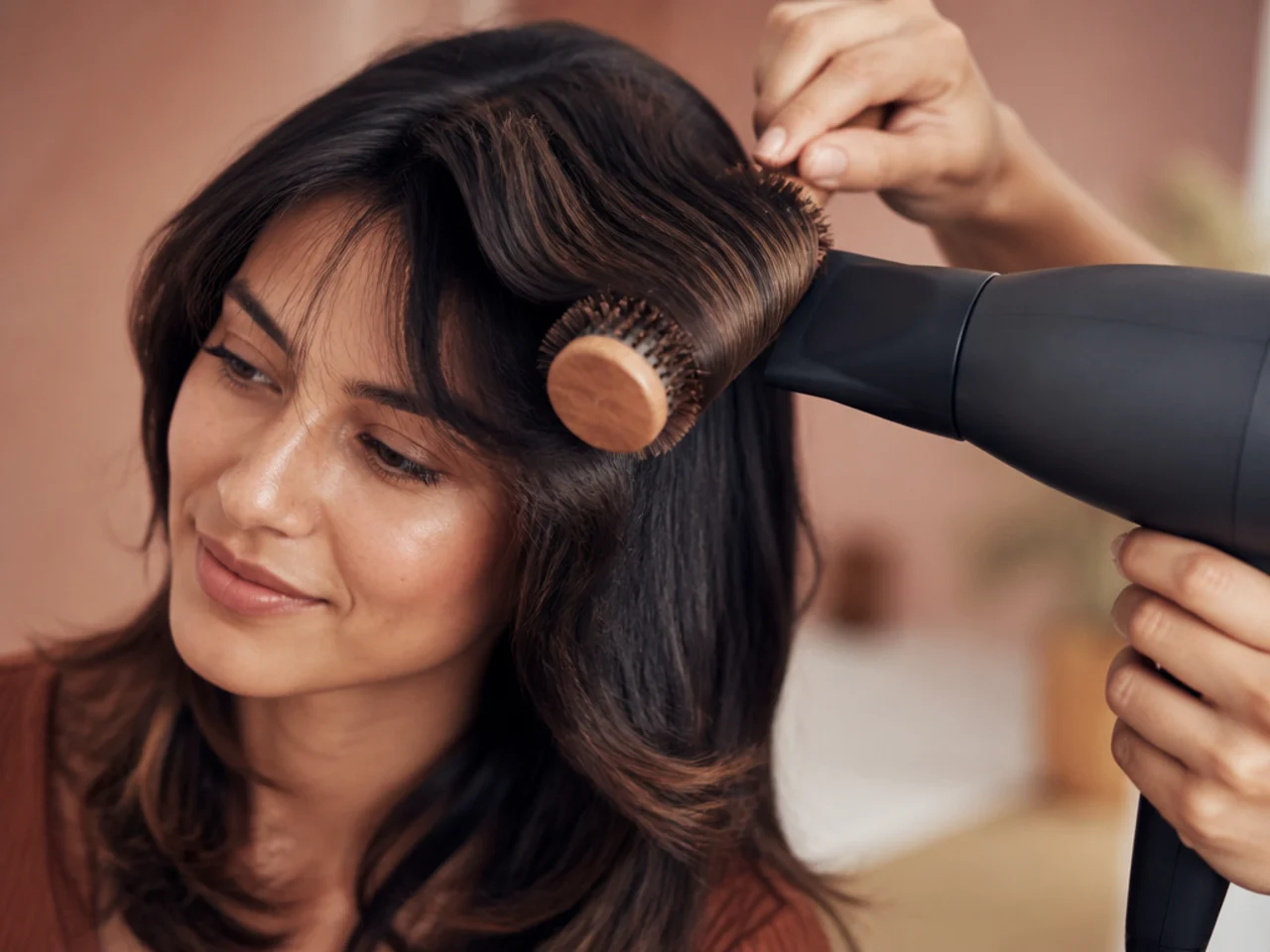 A dryer set to cool aimed at a fringe still wrapped around a round brush