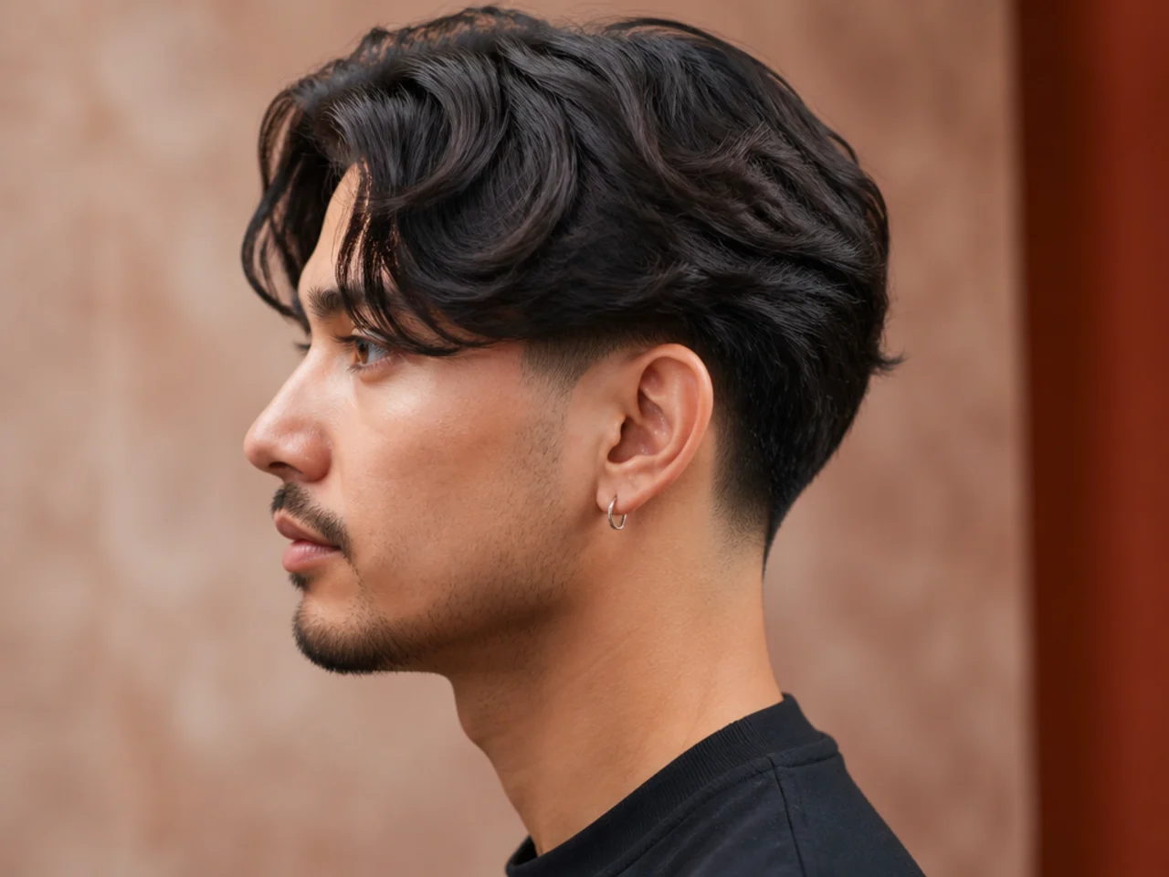 Low taper curtain fade with a subtle blend just above the ear and a four-inch center-parted top on a young man