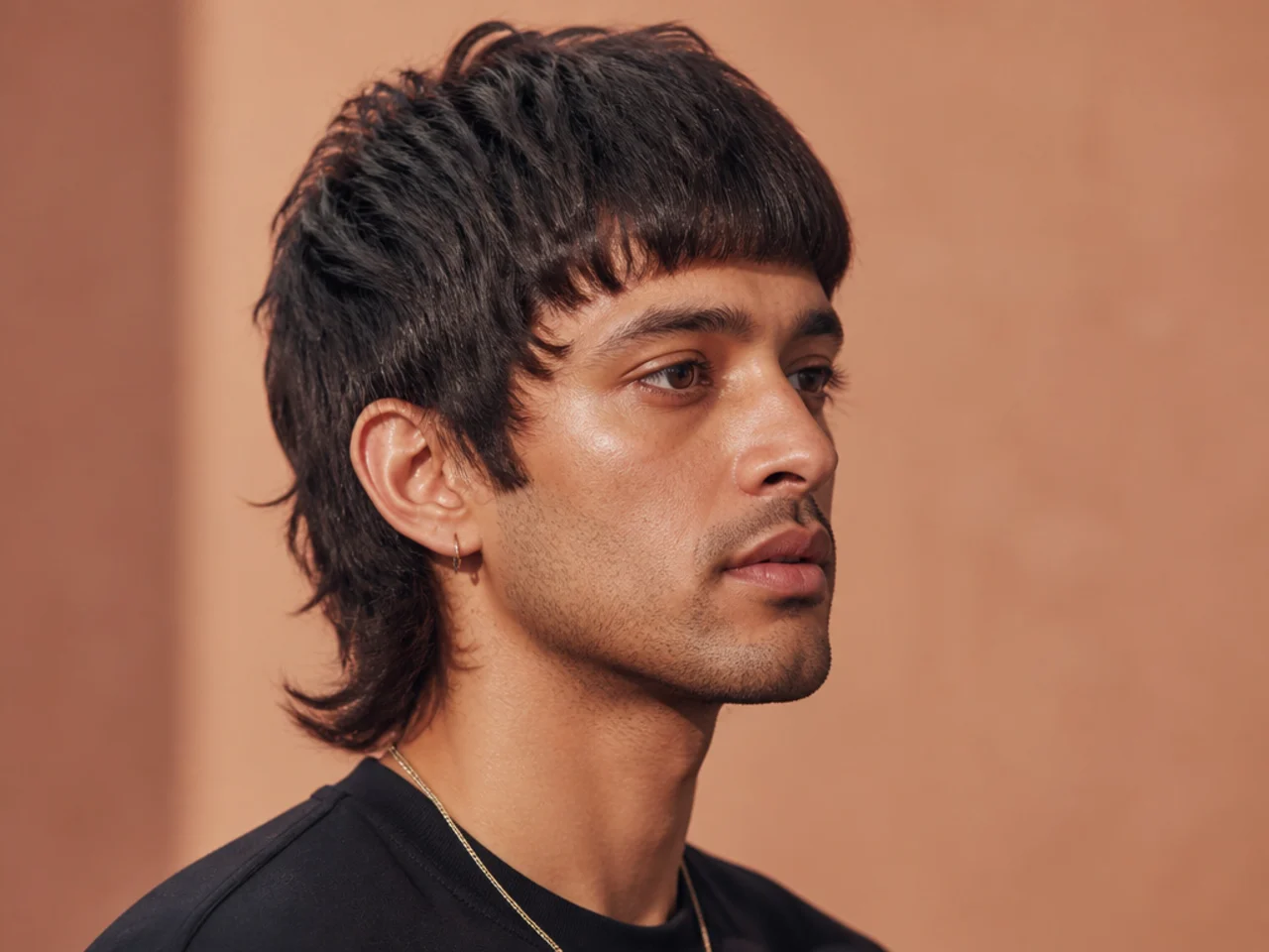 Side-profile diagram of a fringe mullet showing a deliberate forward fringe, textured top, and a layered nape at the collar