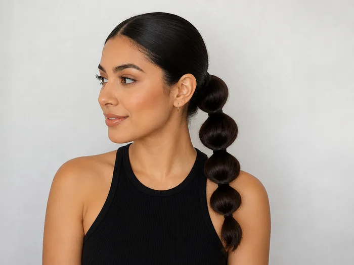 Woman with a sleek low bubble ponytail, medium length hair sectioned into bubbles