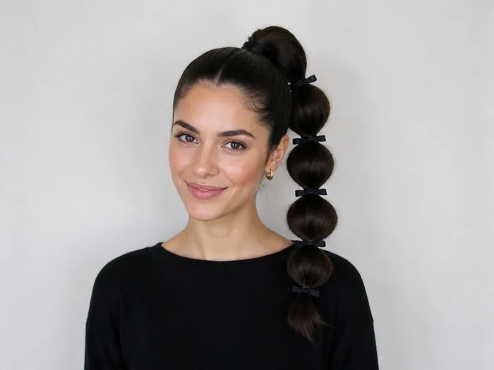 Woman with a bubble ponytail tied with black ribbon sections for a Halloween work party