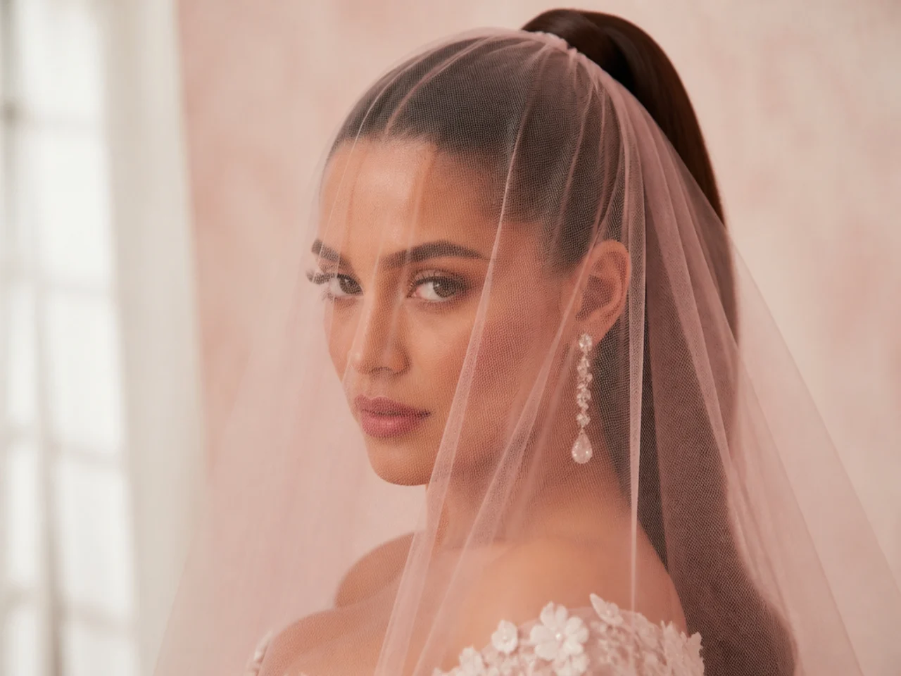 Bride in a soft blusher veil covering her face, worn over a sleek high ponytail