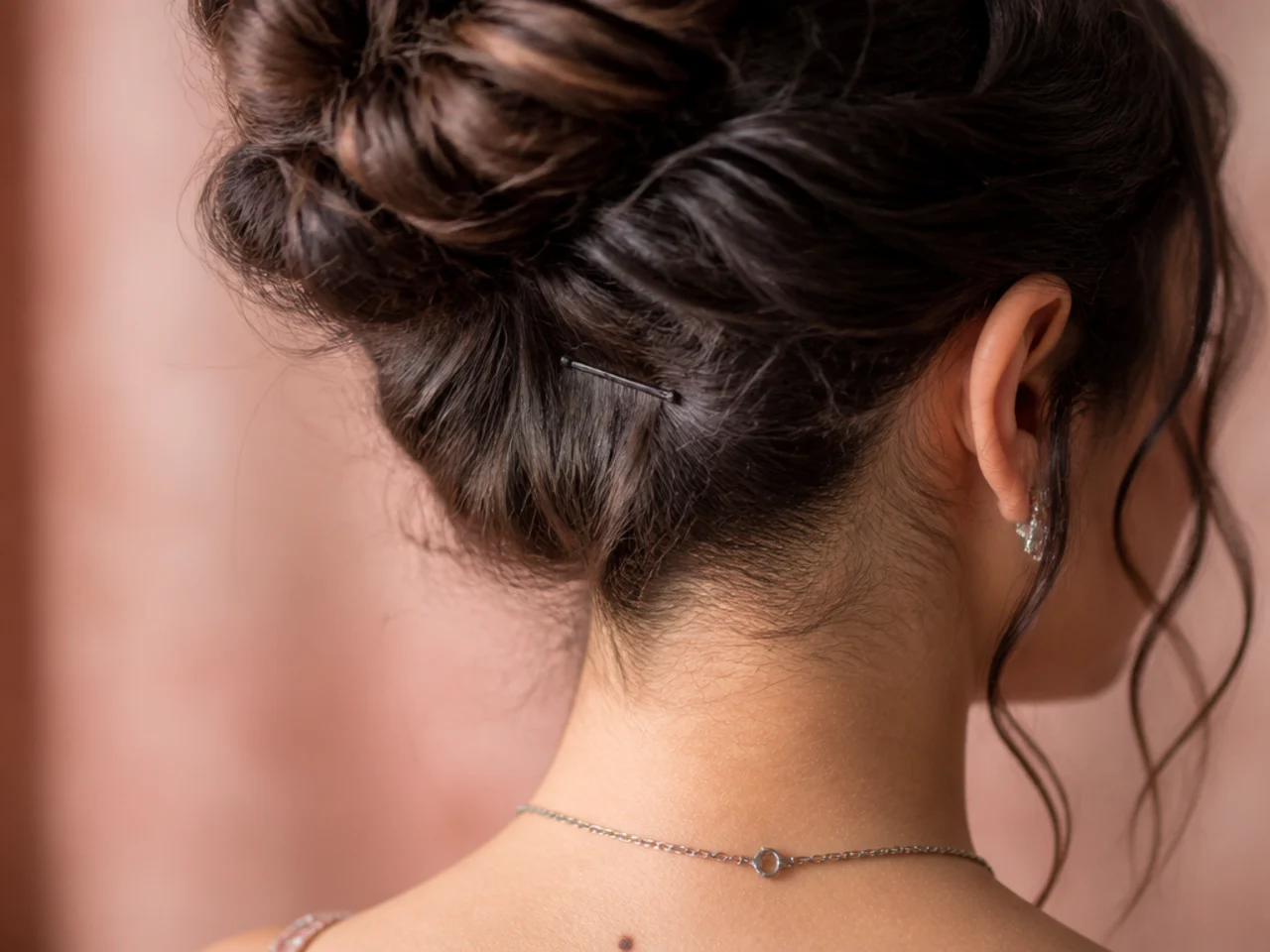 Close view of a bobby pin catching the scalp layer beneath a coiled bun