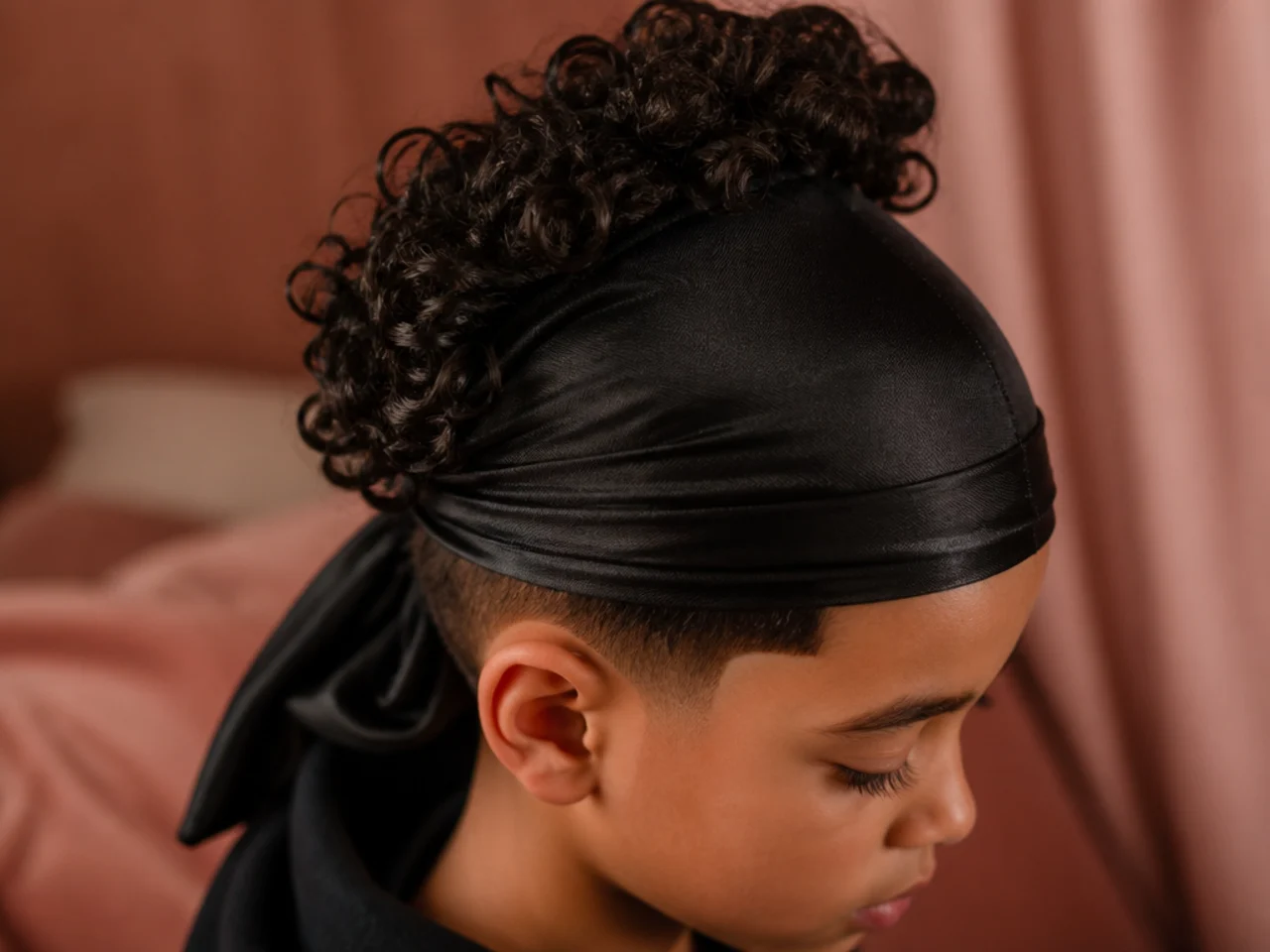 A boy with curls gathered loosely at the crown for bed