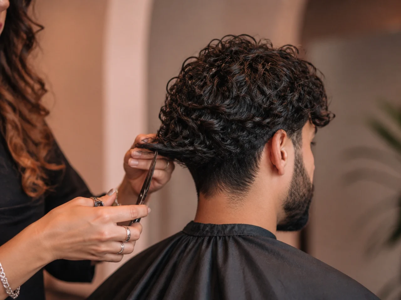 A stylist cutting interior layers into long curly hair