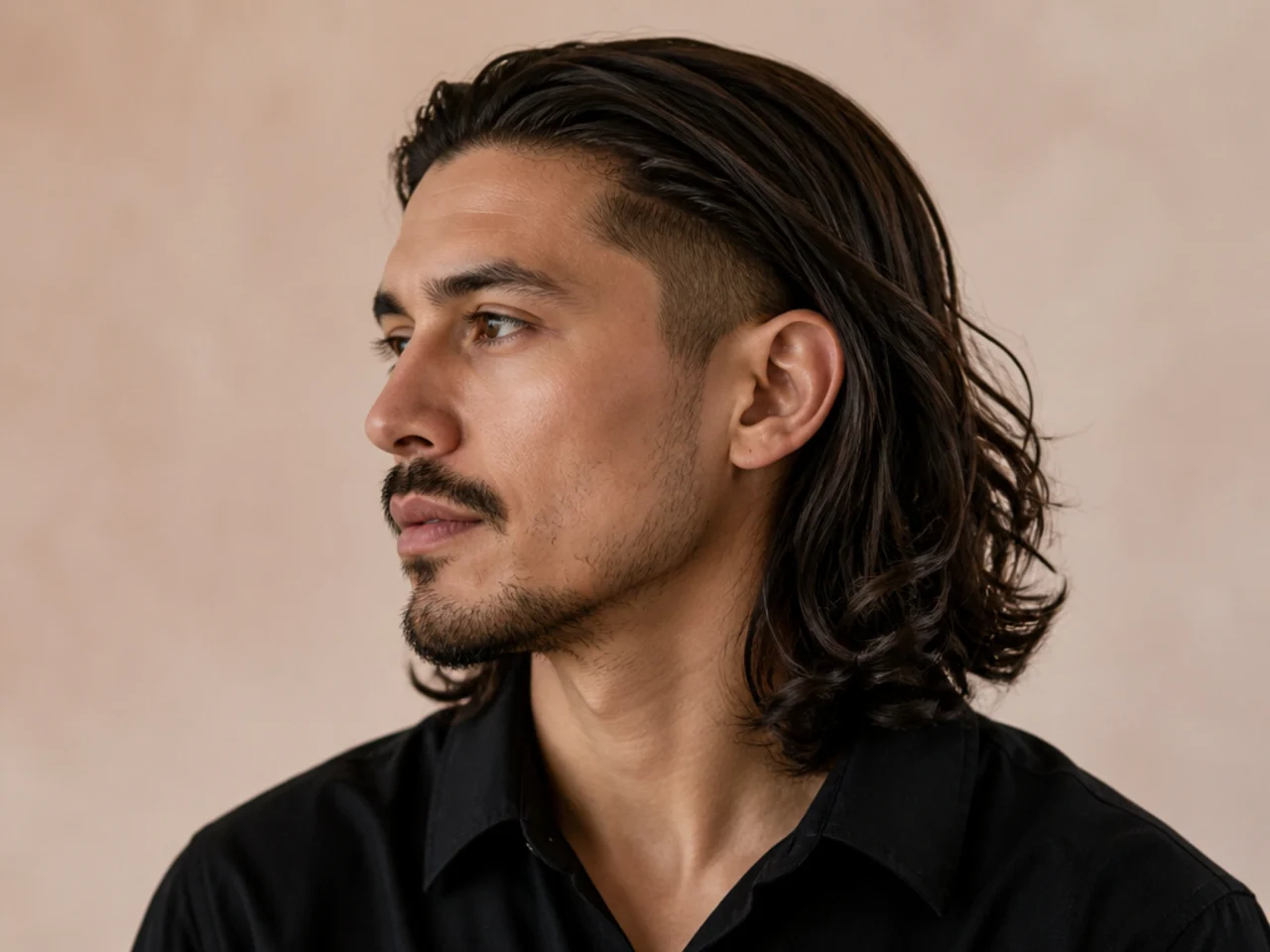 Young man lifting long hair to reveal a hidden undercut buzzed at the nape and behind the ears