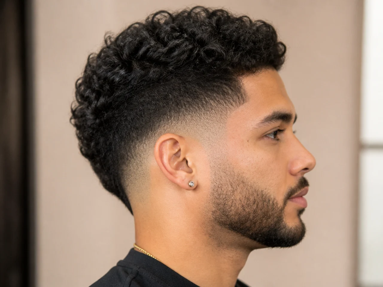 Drop fade arcing downward behind the ear on curly hair