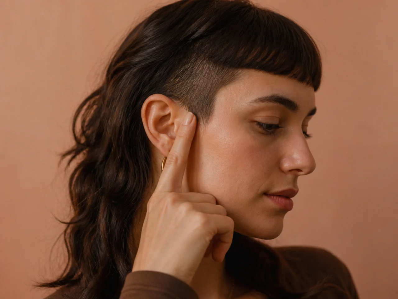 A finger tracing the line from the temple to behind the ear where short meets long