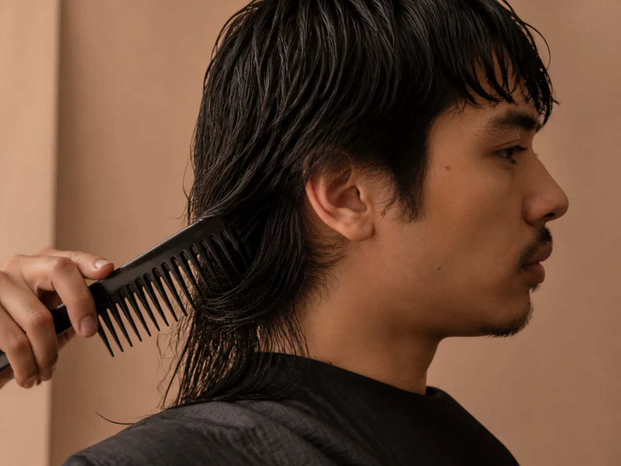 A wide tooth comb working through the damp long back section of a mullet