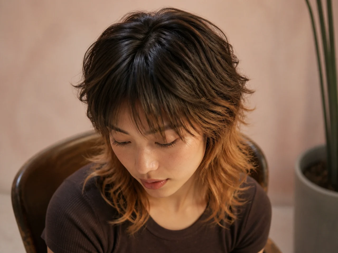 A mullet with visibly darker roots blending into lighter mid lengths, overhead angle