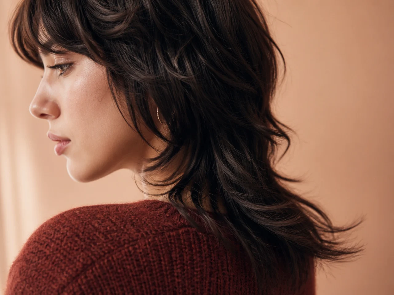 A mullet tail bending outward where the ends meet the shoulder of a knit sweater