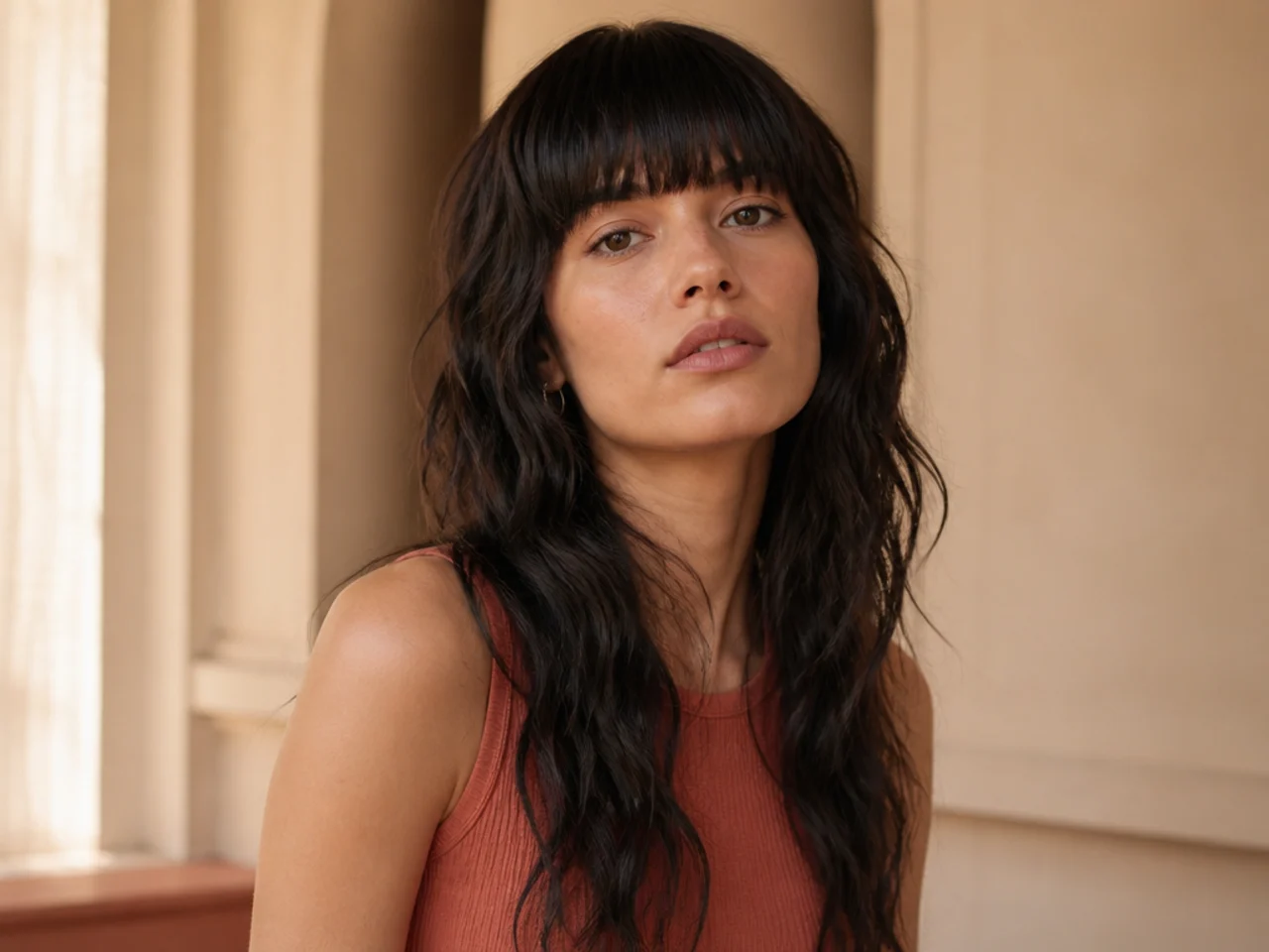 A thick blunt fringe cut to the eyebrows above long wavy mullet lengths