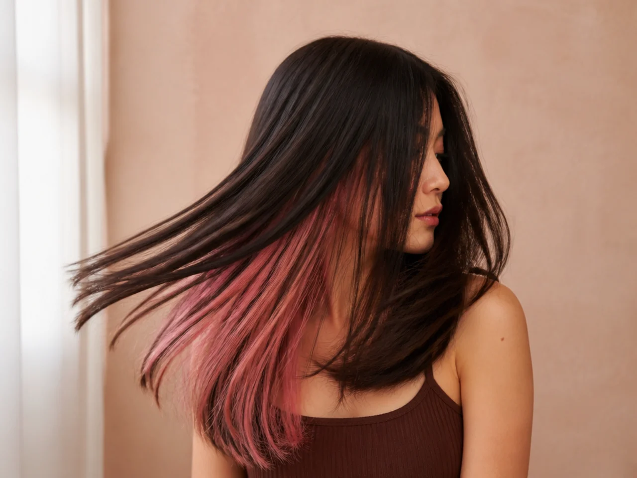 Straight dark hair swinging to reveal a pink panel beneath