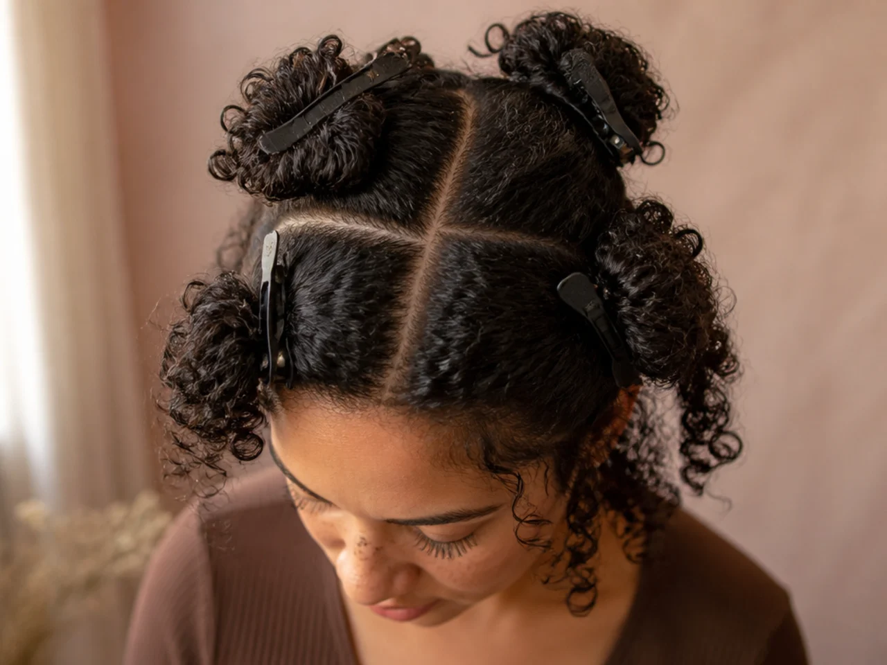 Dry curly hair divided into four clipped quarters with a centre and ear-to-ear parting
