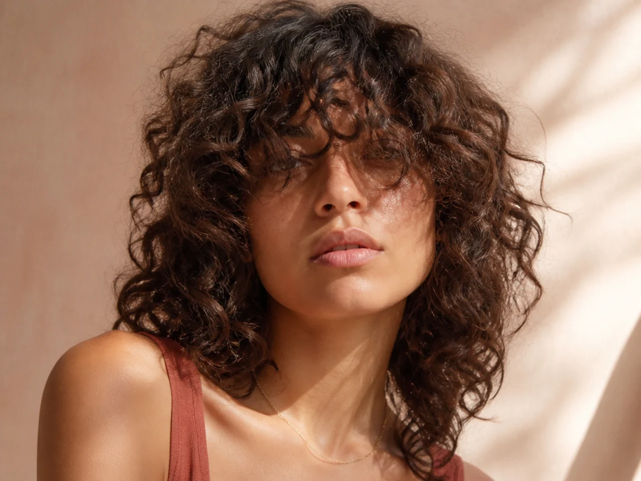 An overgrown curly fringe hanging into the eyes with the parting lost