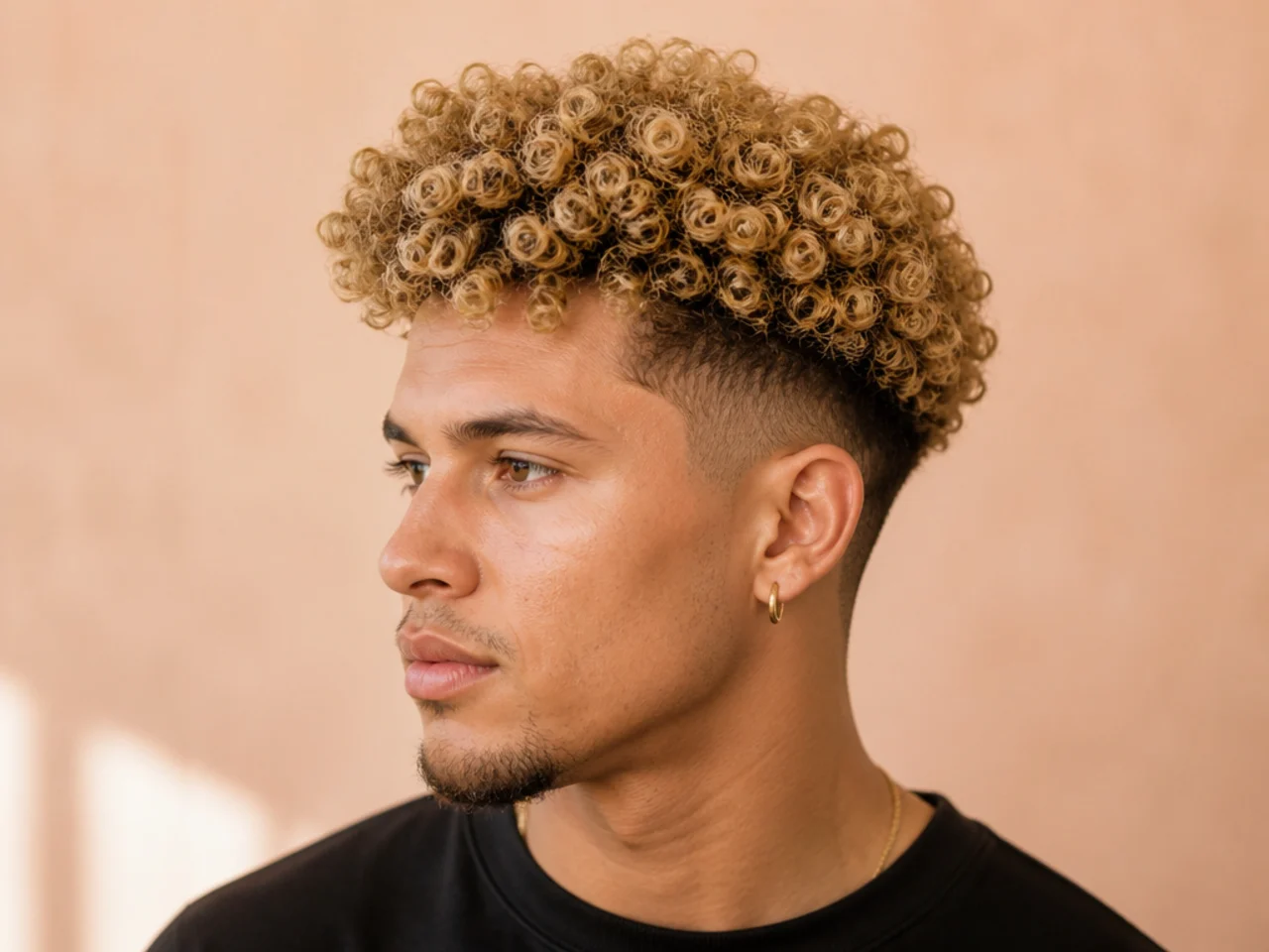 Golden blonde broccoli haircut with tight curls on top and a low taper fade