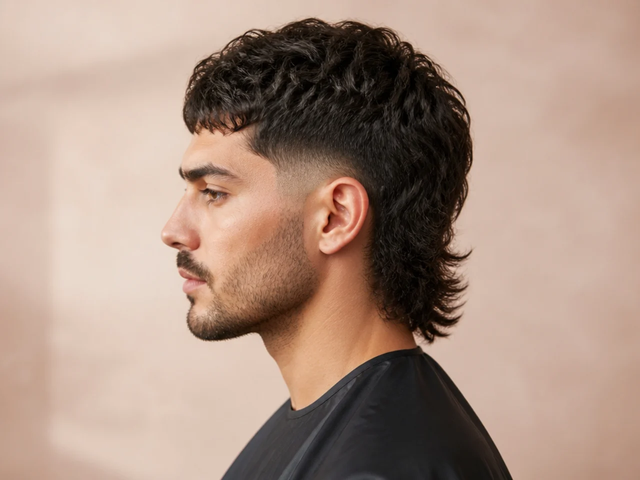 Mid-fade precision mullet on a young man with a sharp mid fade at the temple and a textured three-inch layered mullet back