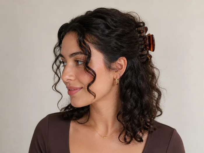 Woman with a curly half-up claw clip twist, front curls twisted back with a claw clip