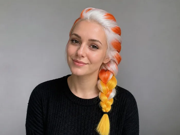 Woman with a long braid in candy corn bands of white, orange and yellow temporary hair color
