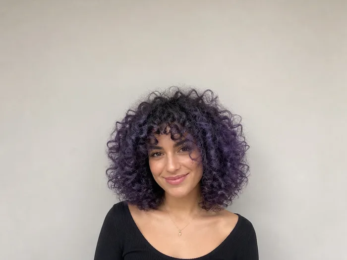 Woman with voluminous curls colored midnight purple with temporary hair chalk