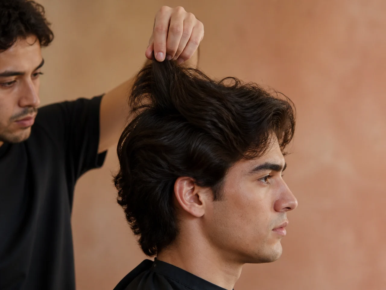 A barber lifting a section of thick hair to show layer length against the head