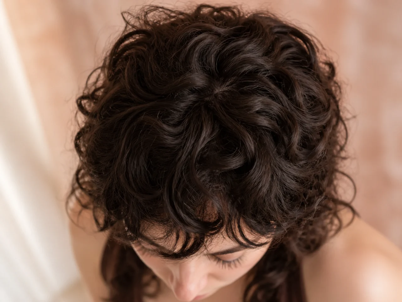 Overhead view of the crown of a curly wolf cut showing the shortest layer