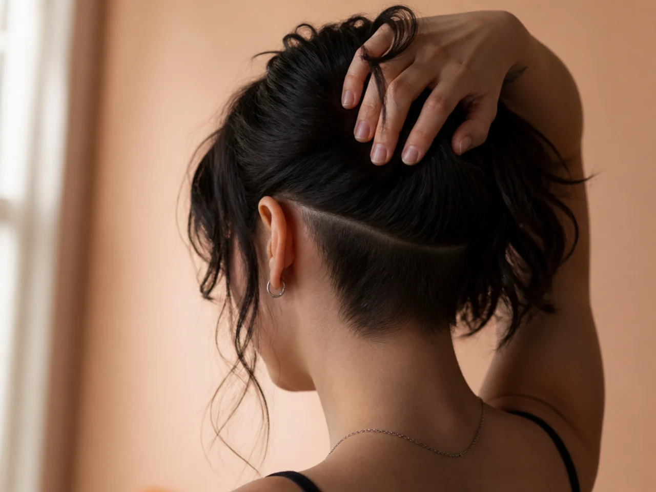 Hair lifted at the nape to reveal a small shaved undercut section beneath a wolf cut