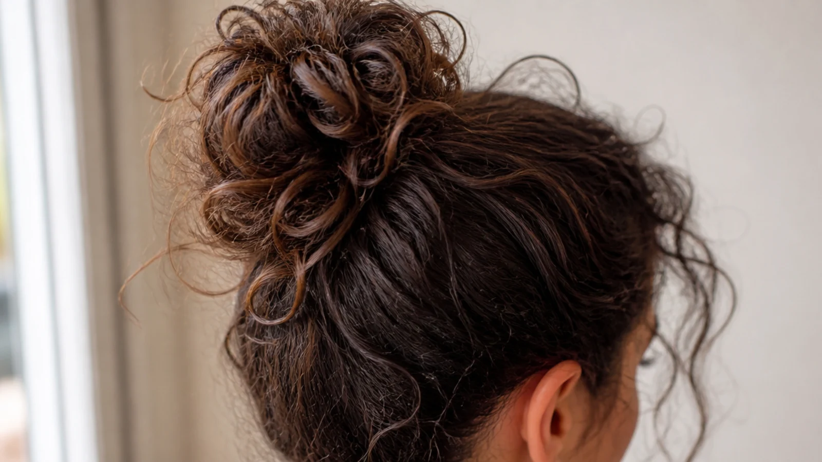 A high curly bun with a few loose pieces left around the face