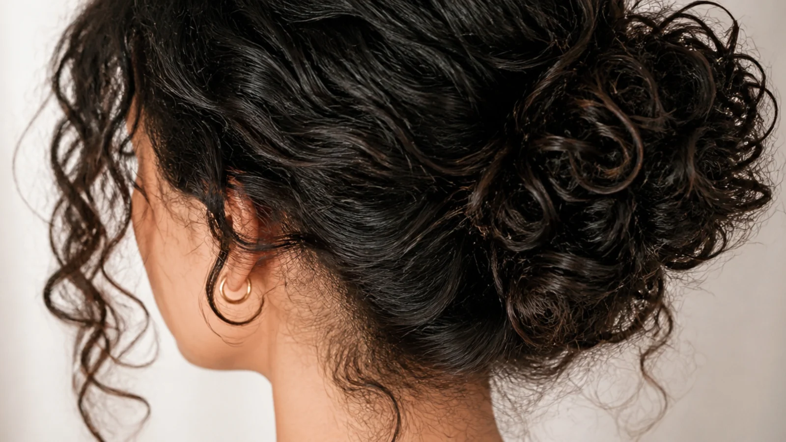 A small bun at the crown with curls left down at the back