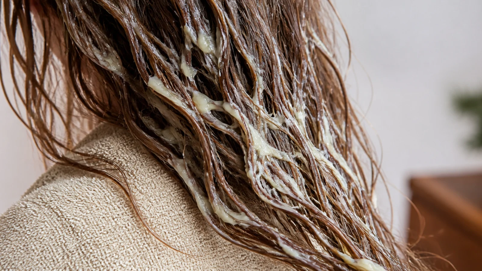 A spoonful of mayonnaise being worked through a section of hair