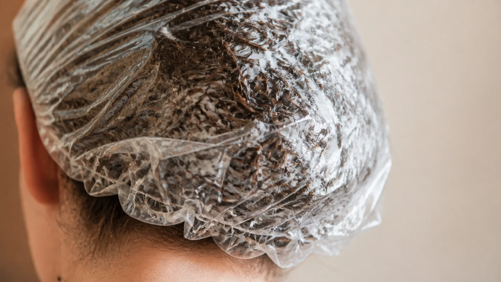 A shower cap over hair coated in deep conditioning mask