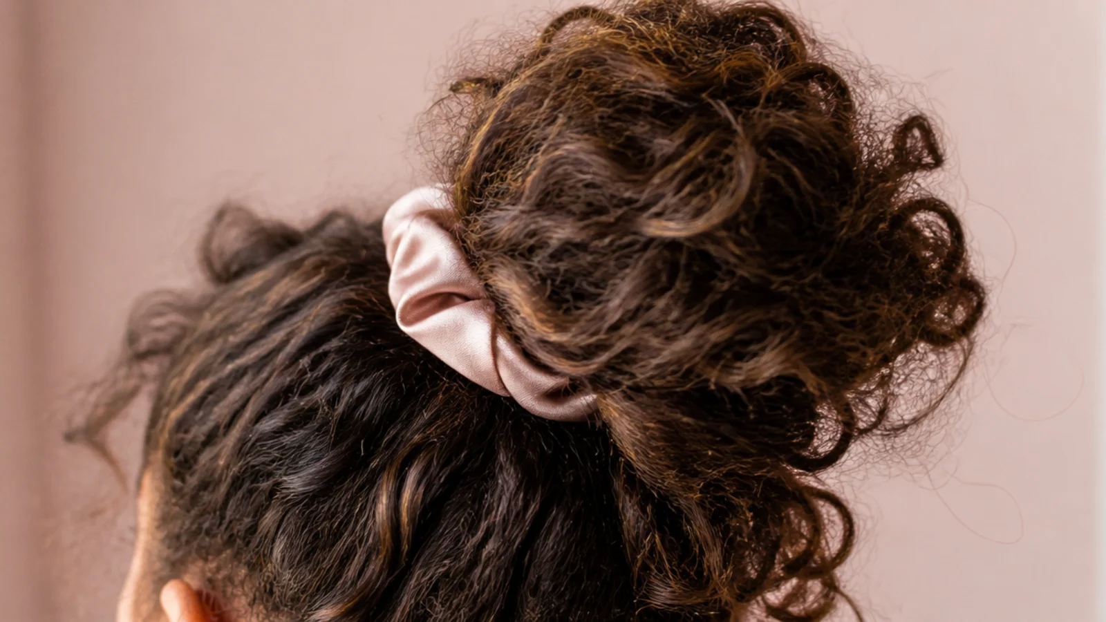 Curls gathered loosely on top of the head in a high pineapple