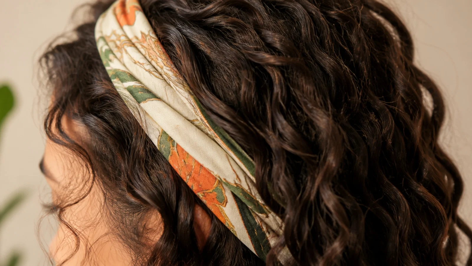 A patterned silk scarf tied as a wide band across the front hairline