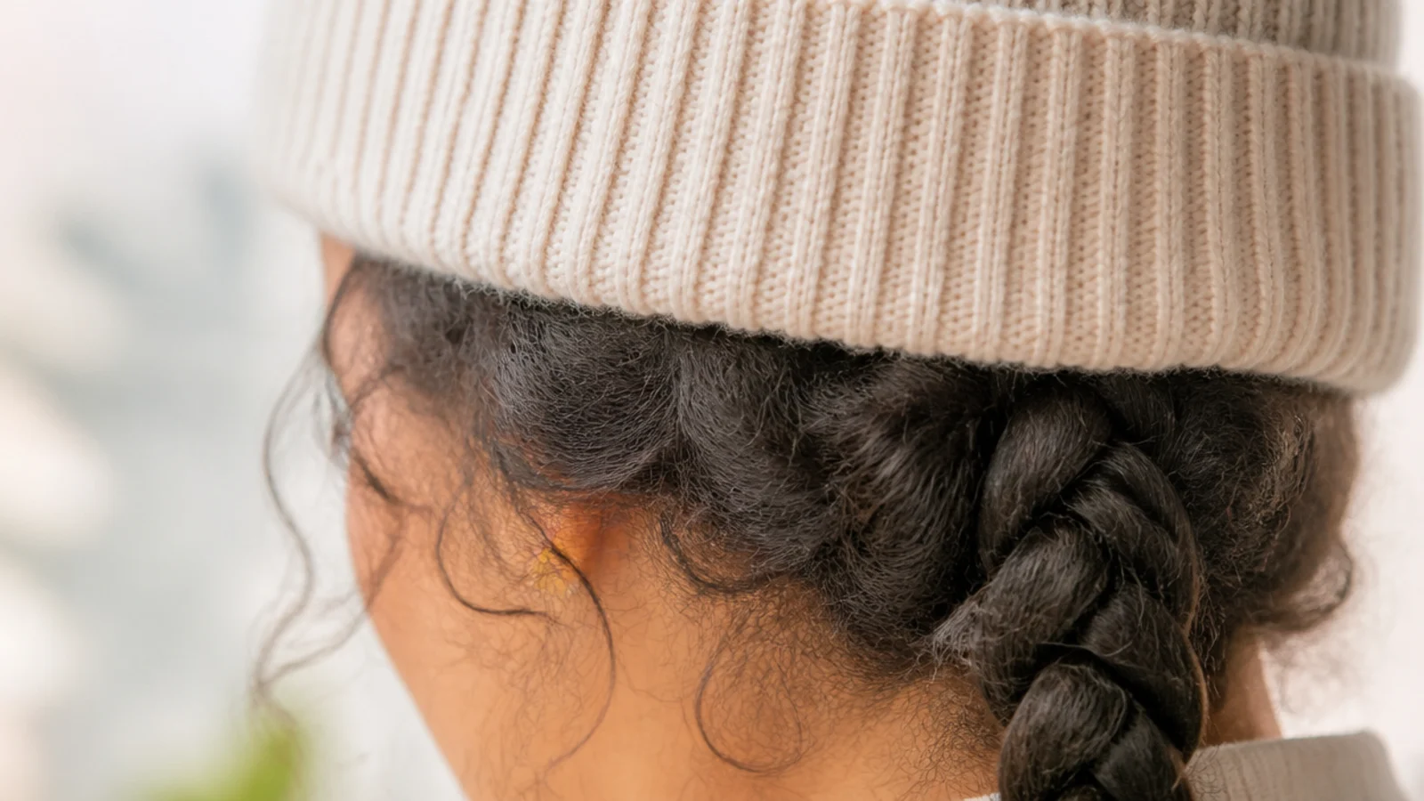 A ribbed beanie worn over a low braid resting on one shoulder