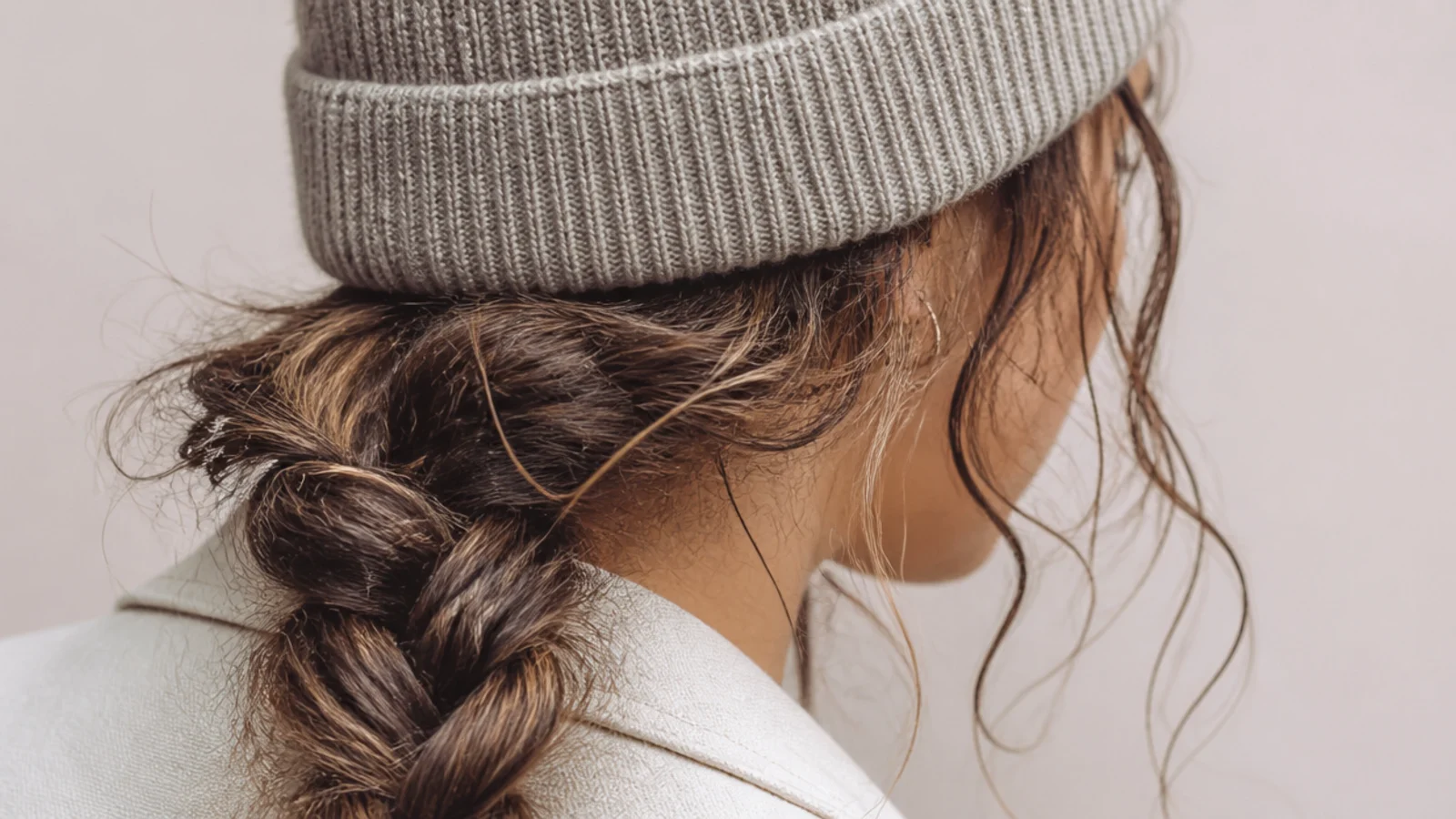 A beanie worn over a low side braid resting on one shoulder