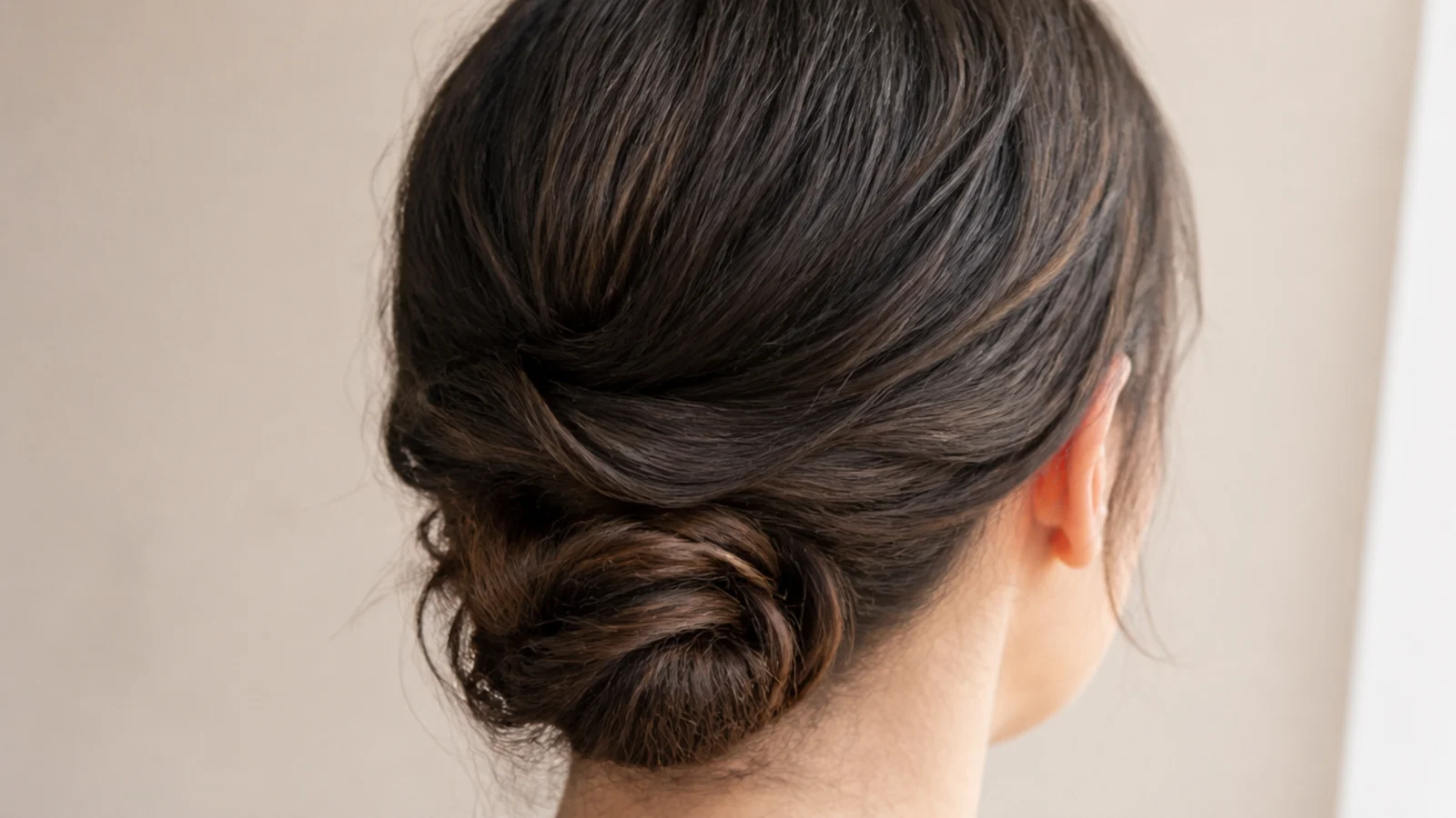 A rolled chignon pinned low at the nape of the neck
