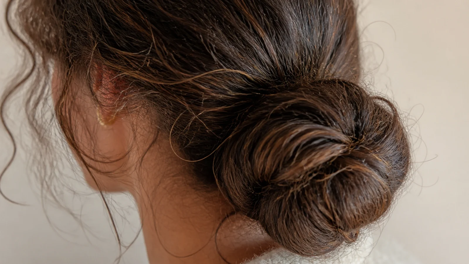 A low rolled bun tucked under and pinned flat against the head