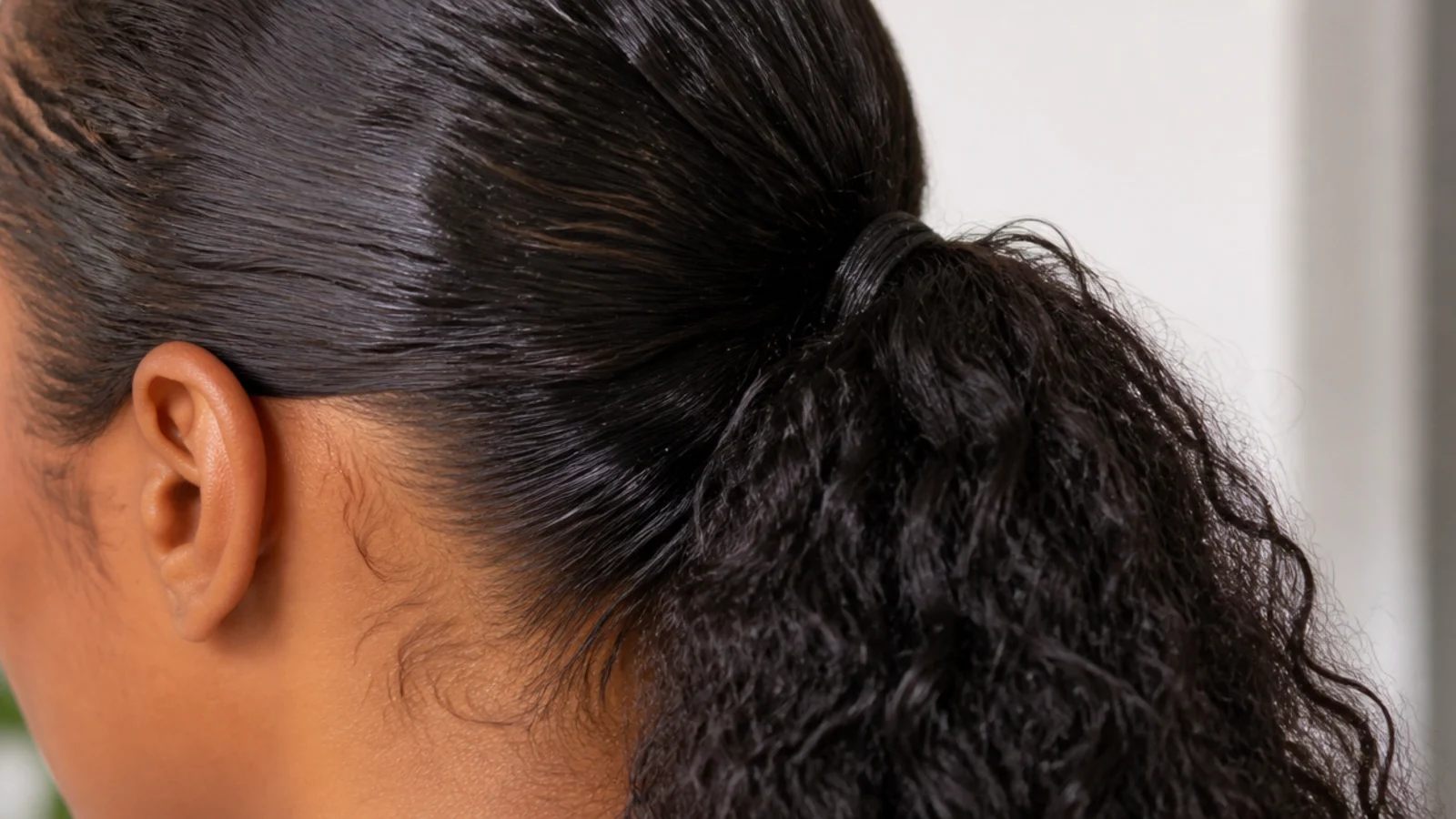 A gel stick being pressed along the hairline above a tight ponytail