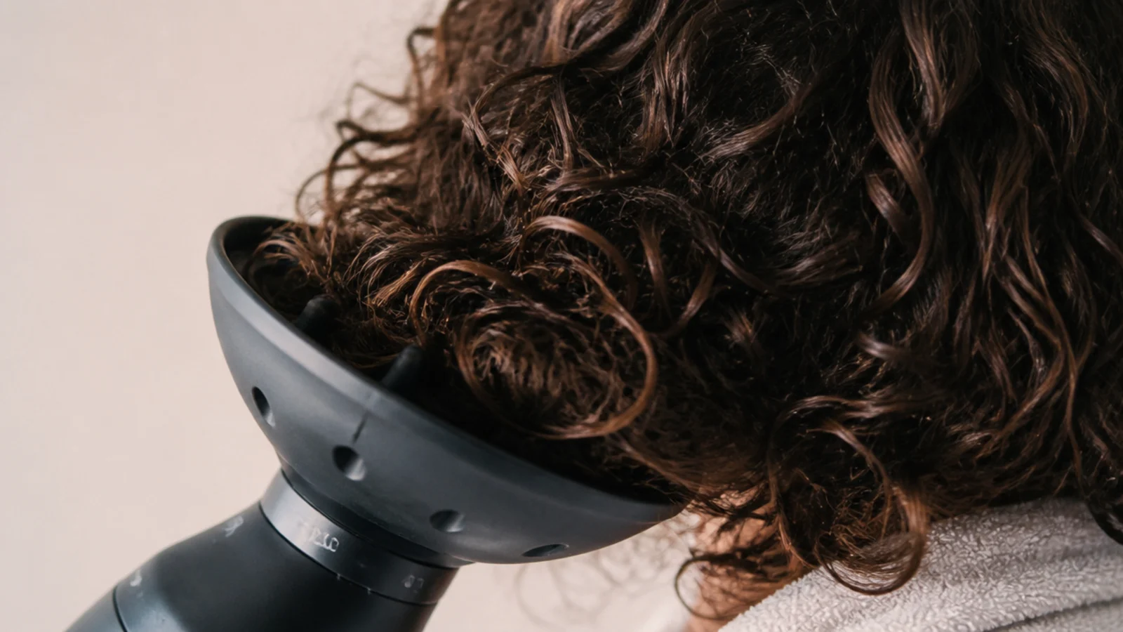 Curls sitting inside a diffuser bowl held cupped against the side of the head