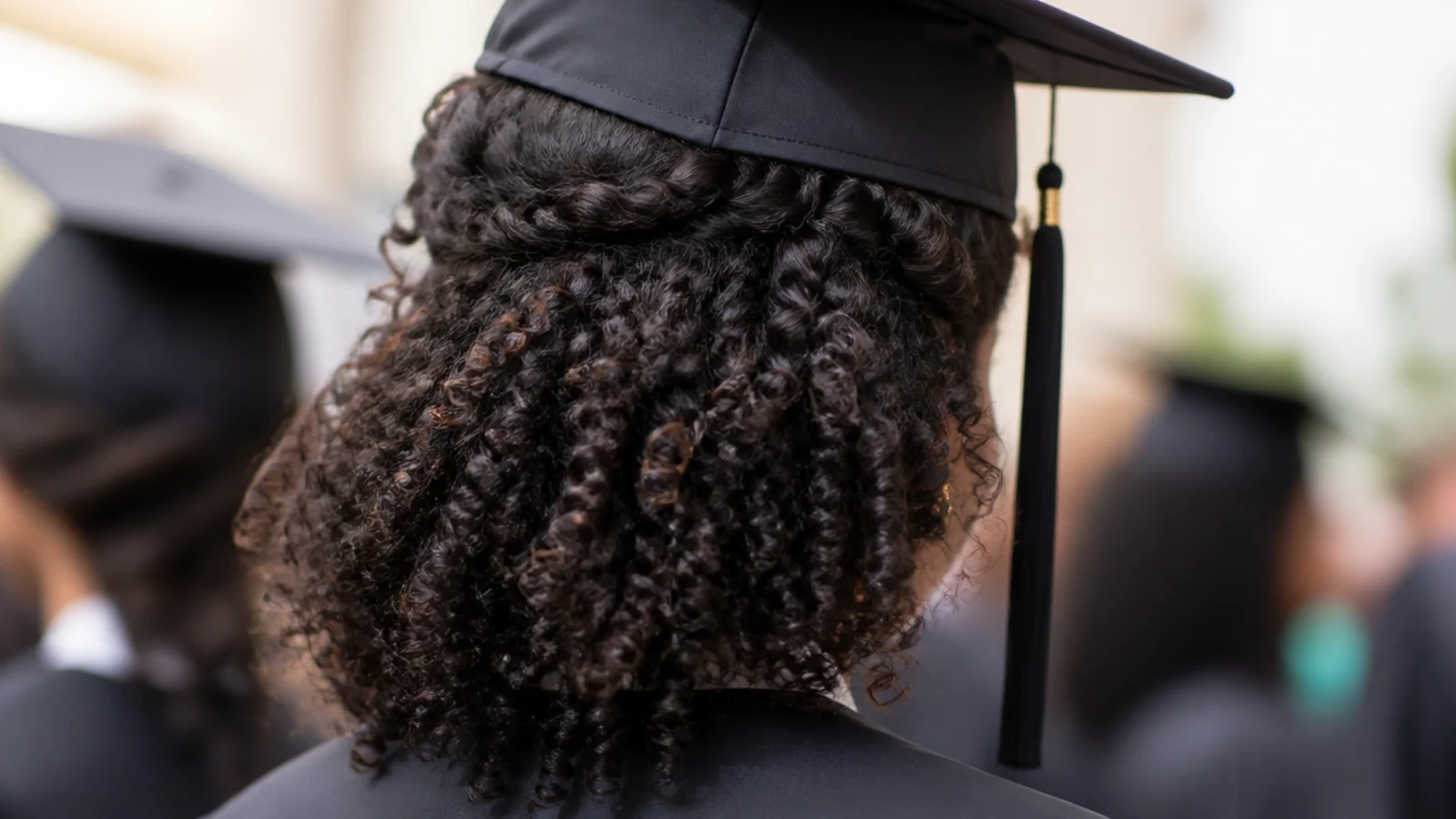 Defined natural curls worn loose beneath a mortarboard