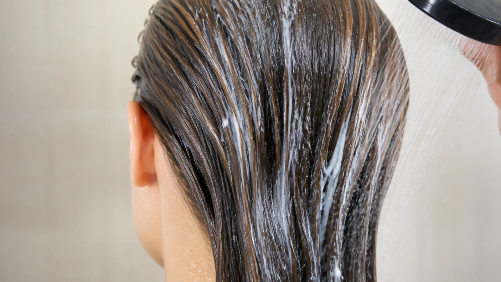 Hair being wetted at a poolside shower before swimming