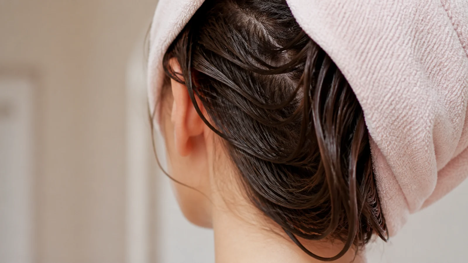 Long wet hair being squeezed inside a microfiber towel