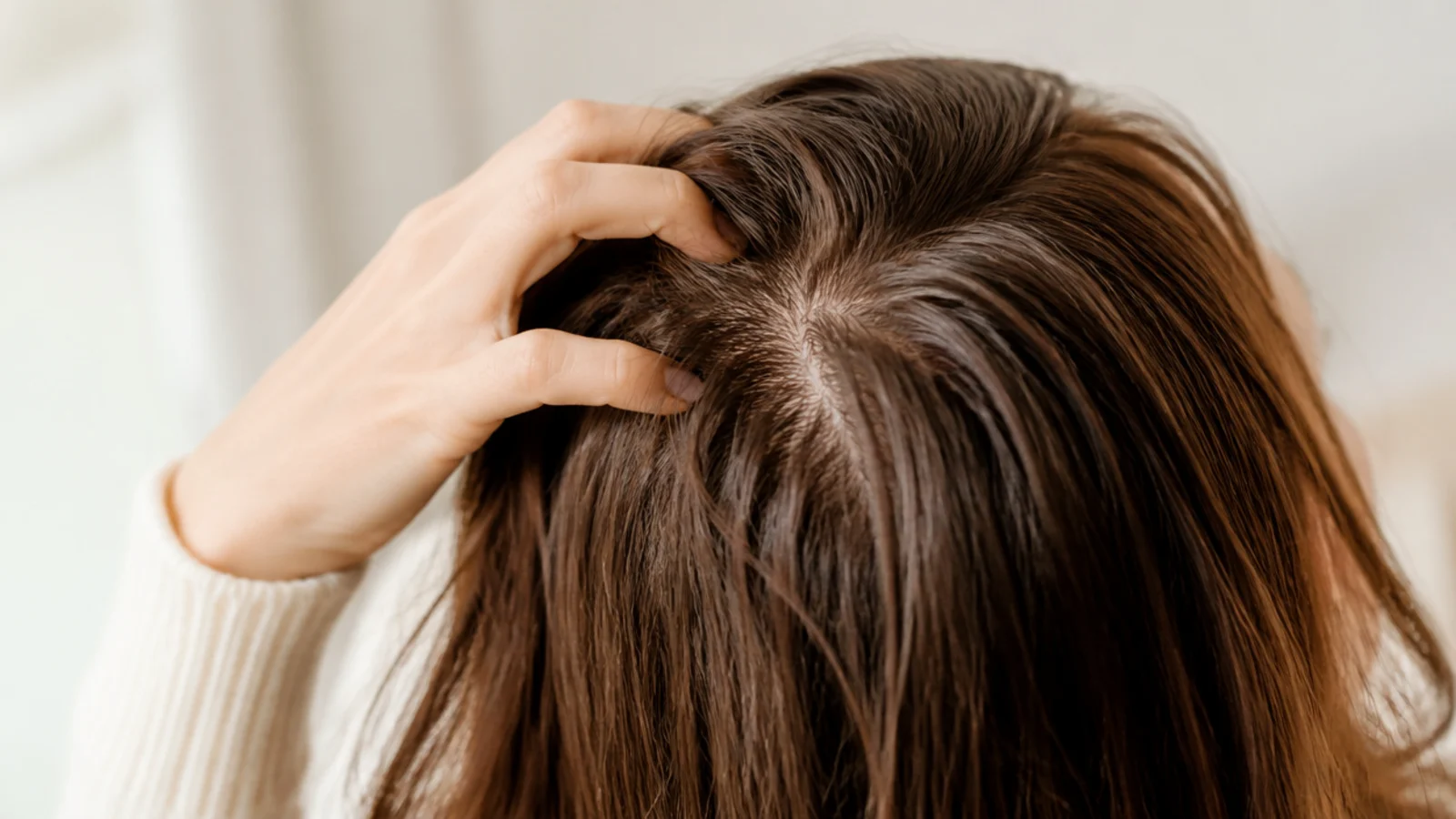 Both hands massaging the crown with long hair swept forward
