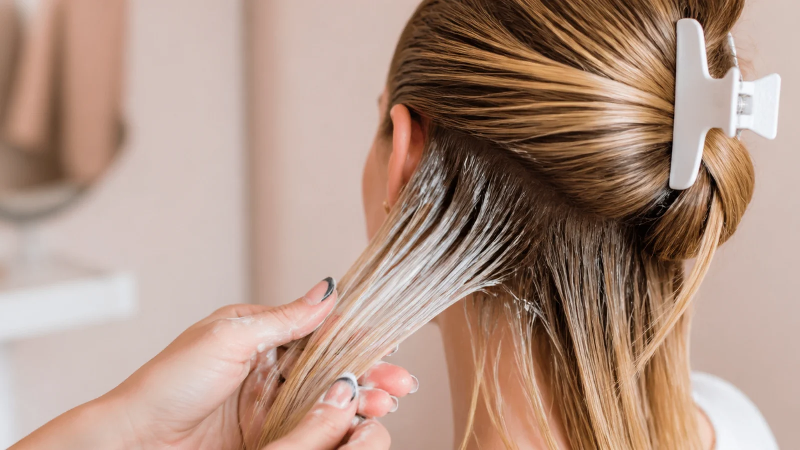 A protein treatment jar open beside a wet section of hair