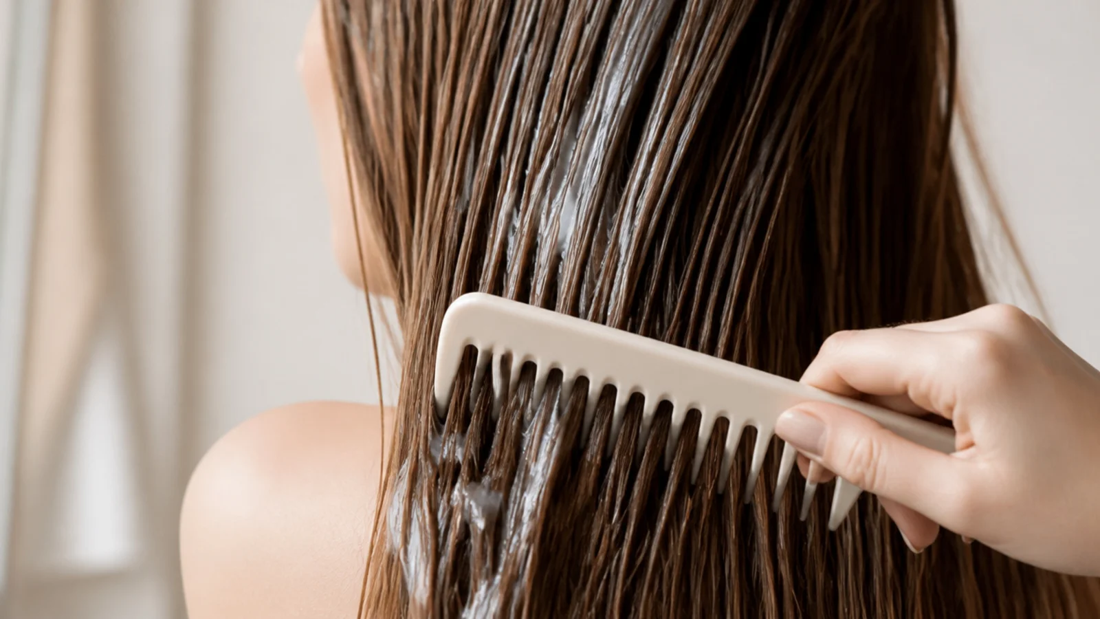 A wide tooth comb working through the ends of damp hair